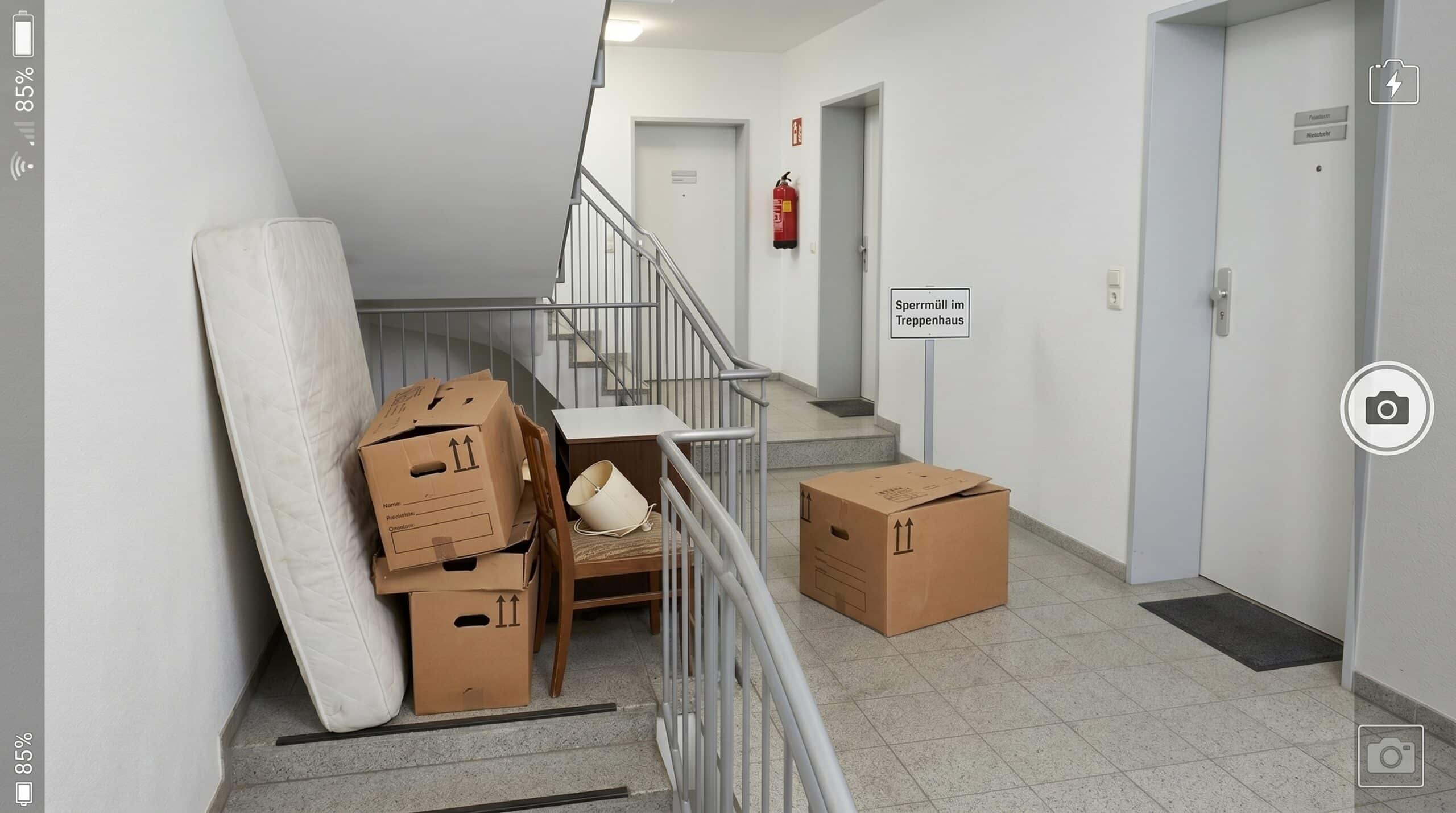 Sperrmüll im Treppenhaus mit blockiertem Laufweg, Fotodokumentation und typischer Treppenhausumgebung in einem Mehrfamilienhaus